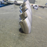 group of 4 45 degree bends standing up with a messy work bench in the back ground