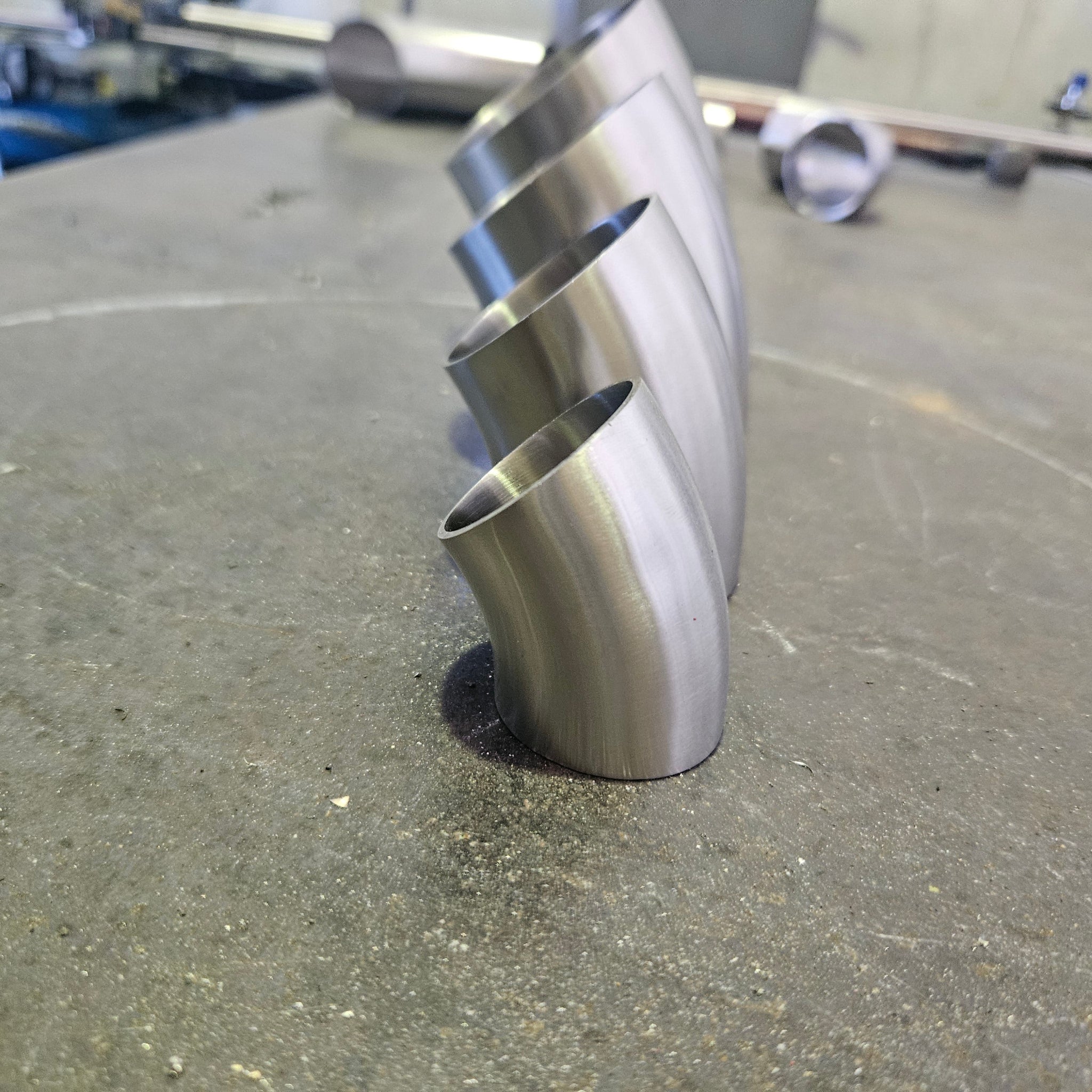 group of 4 45 degree bends standing up with a messy work bench in the back ground 