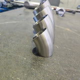 group of 4 45 degree bends standing up with a messy work bench in the back ground 