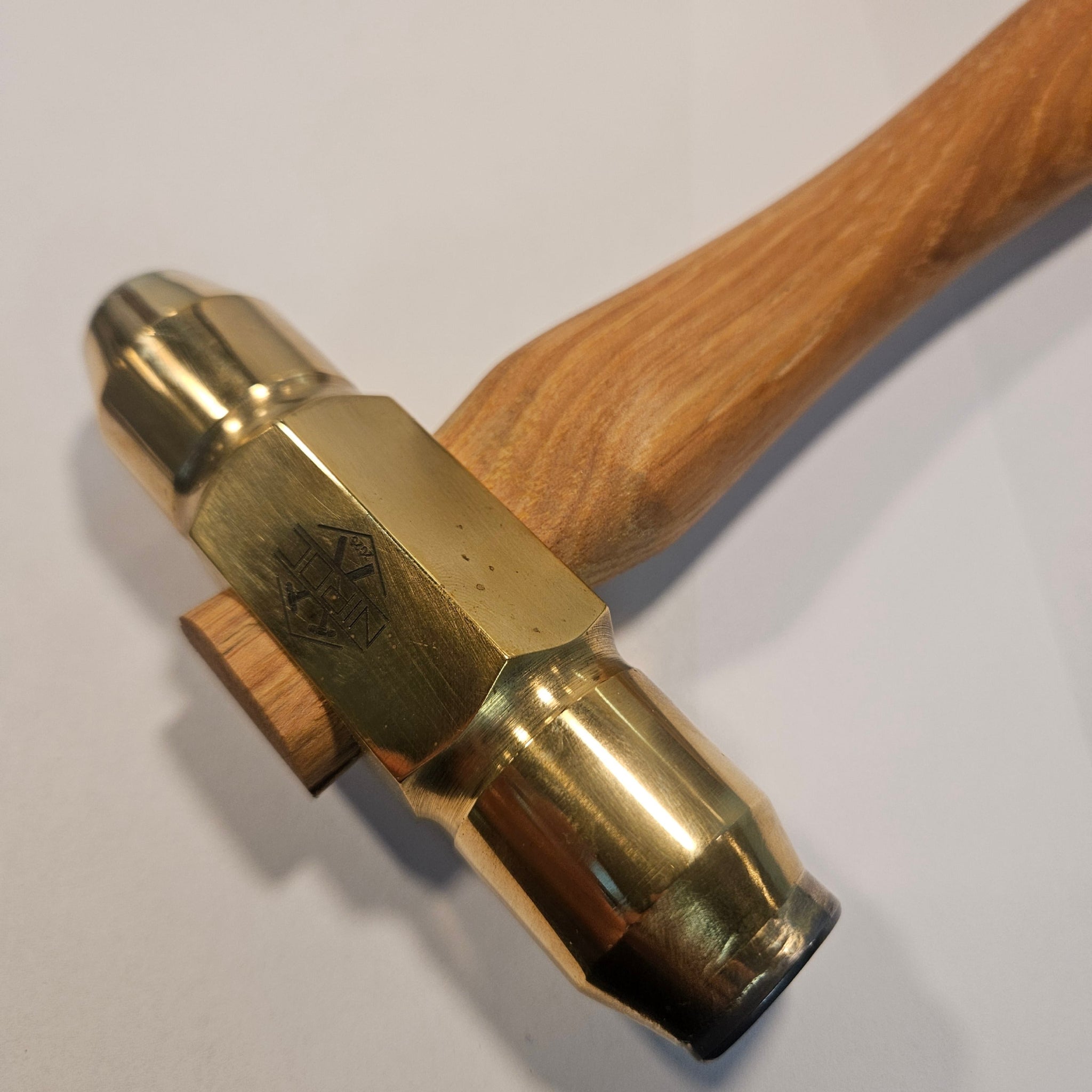 Brass hammer with a flat carbide face and a ball carbide face with wooden handle on a white background