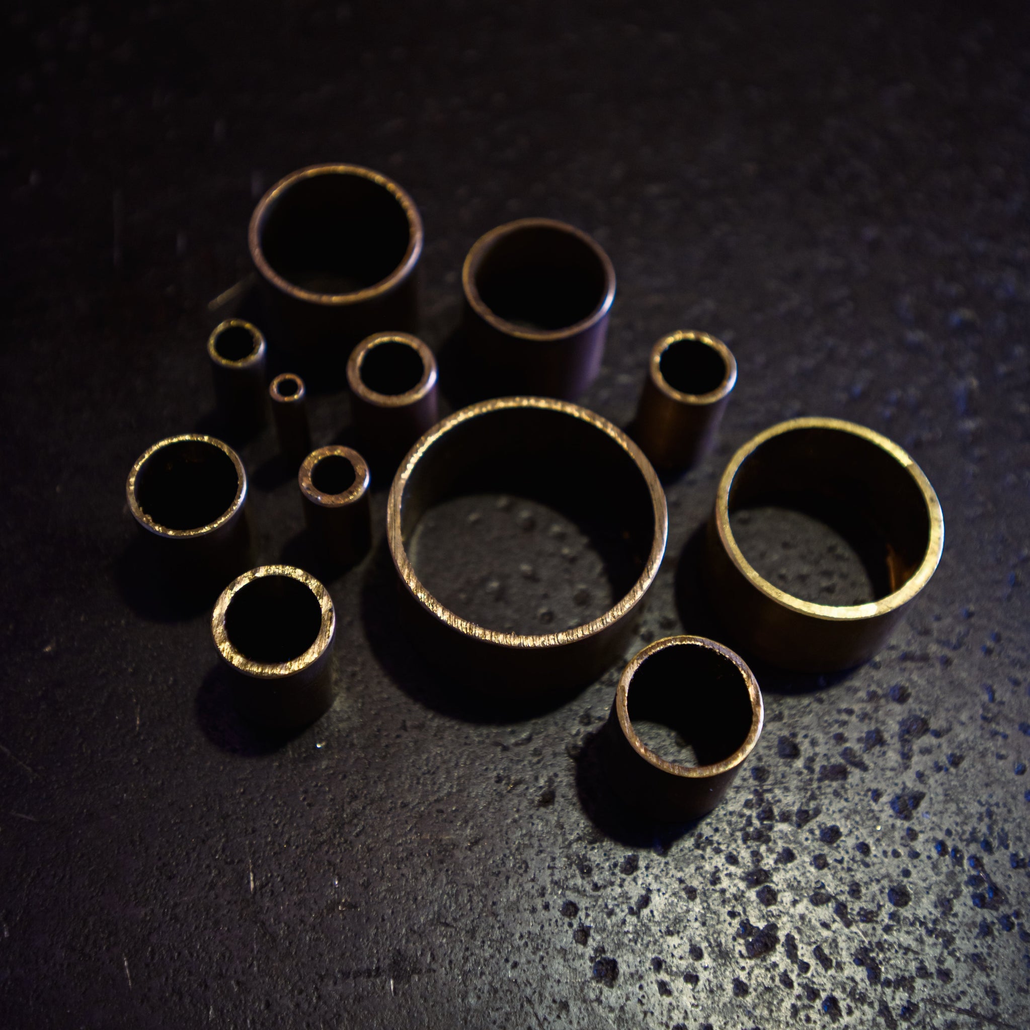 Close-up of brass round tube cut sections showing hollow ends and wall thickness across multiple diameters