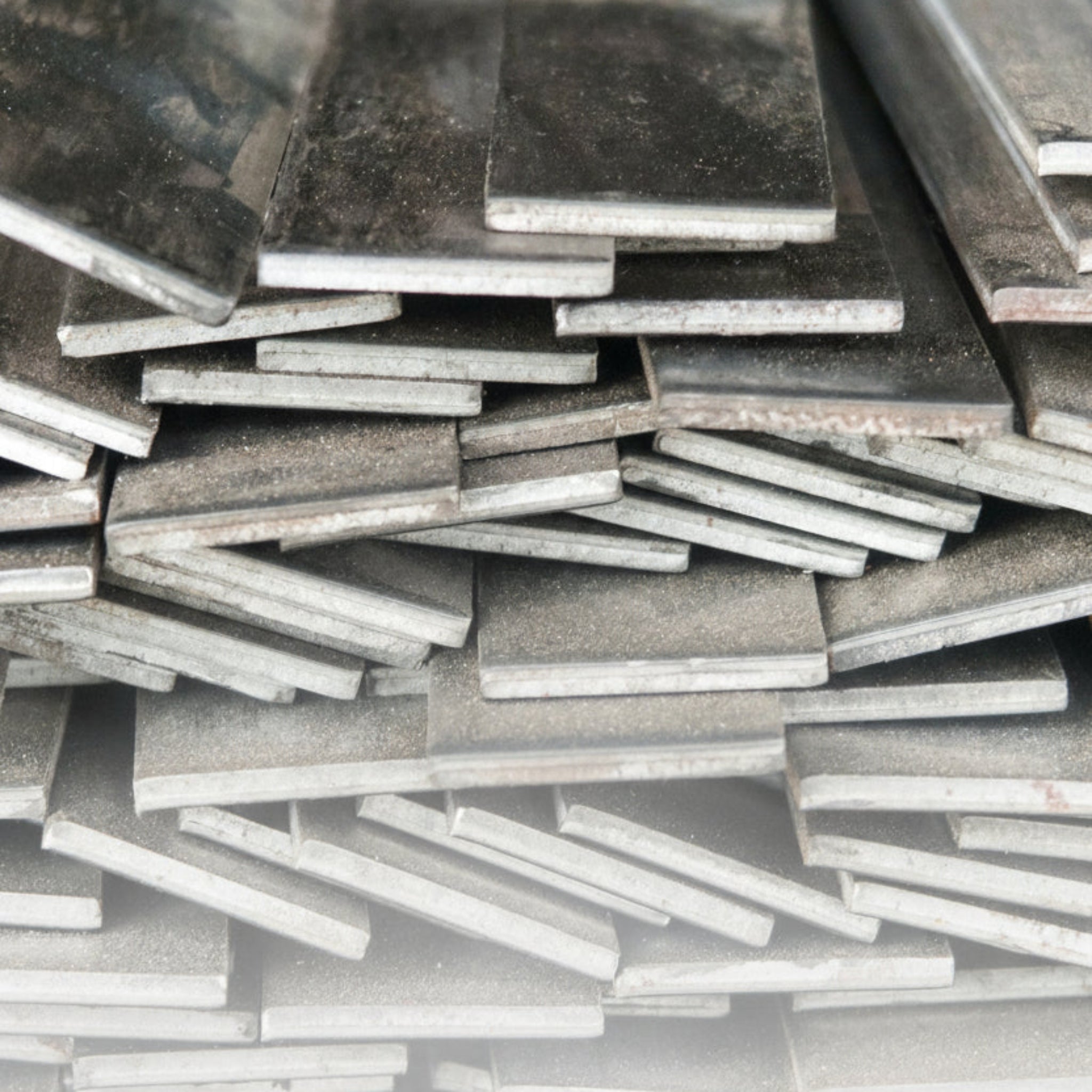 Bundle of stainless steel flat bar cut to different lengths and widths on white background