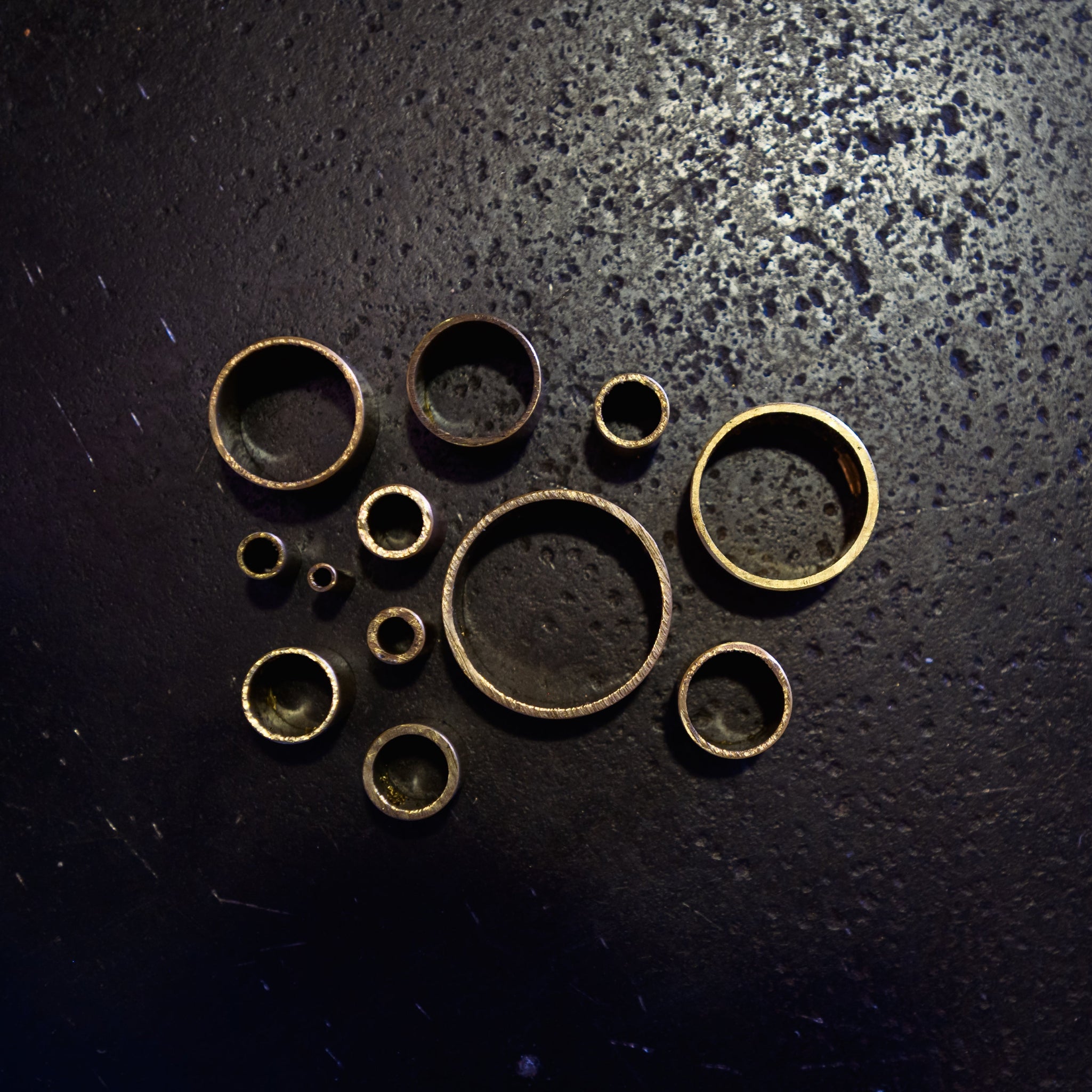 Top-down view of brass round tube cut sections showing range of available diameters on dark background