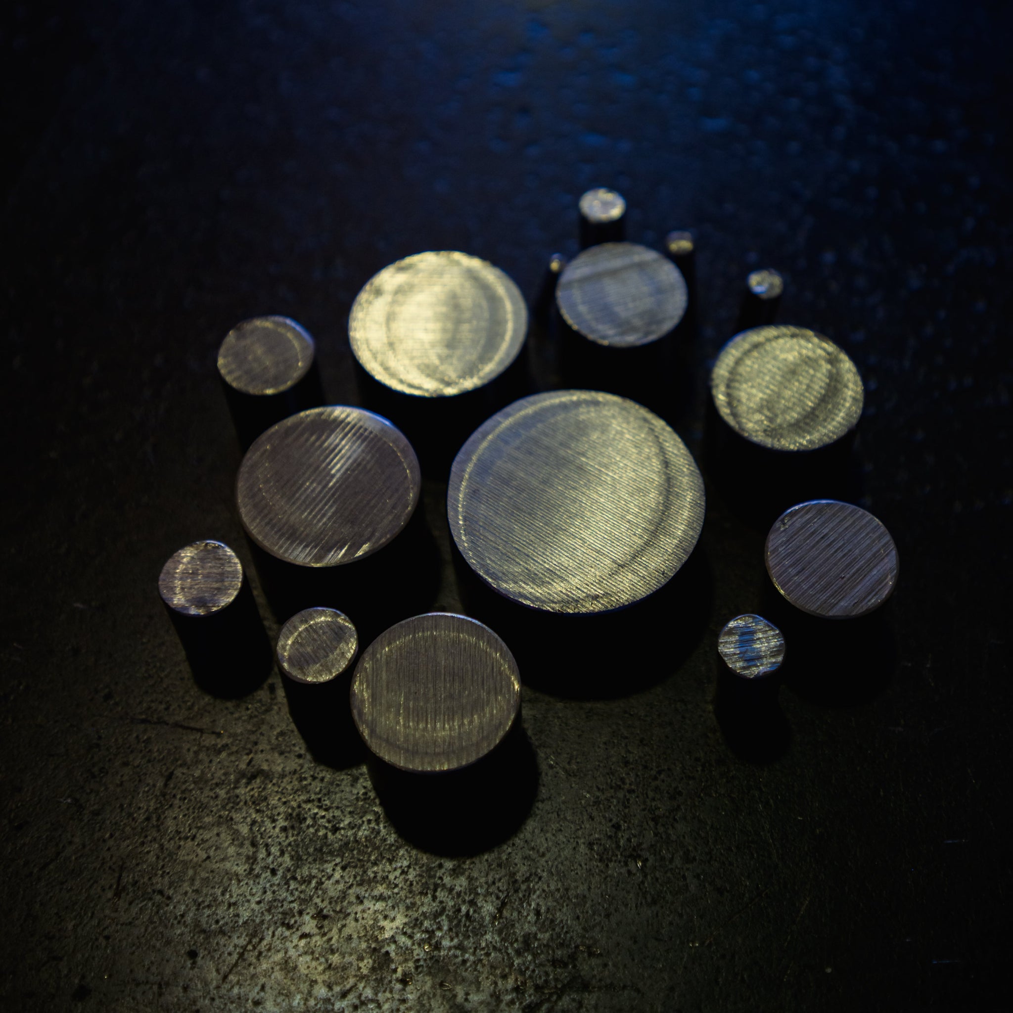 Top-down view of stainless steel round bar cut sections showing range of available diameters on dark background