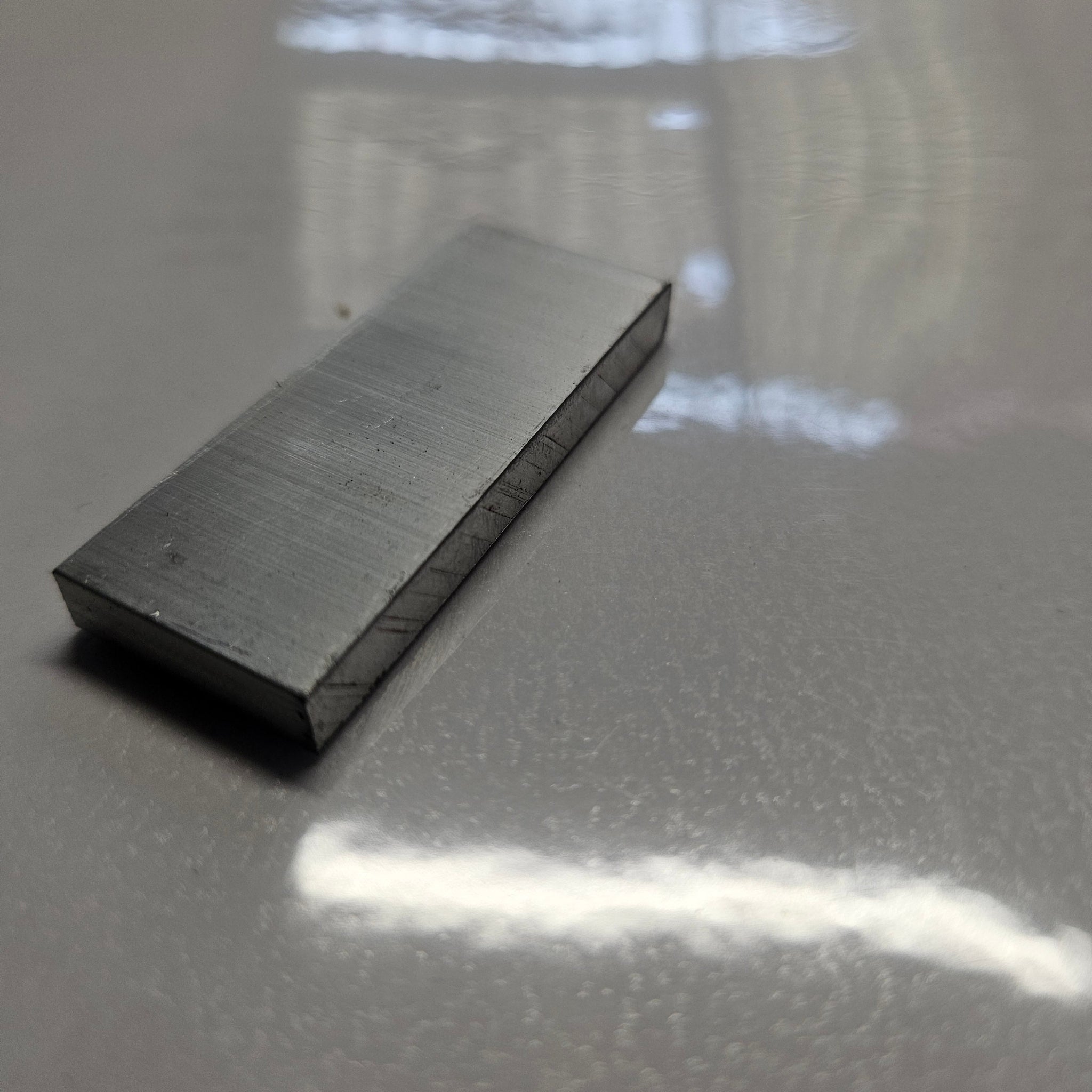 aluminium 6mm x 50mm on a shinny  white background on a downward angled view