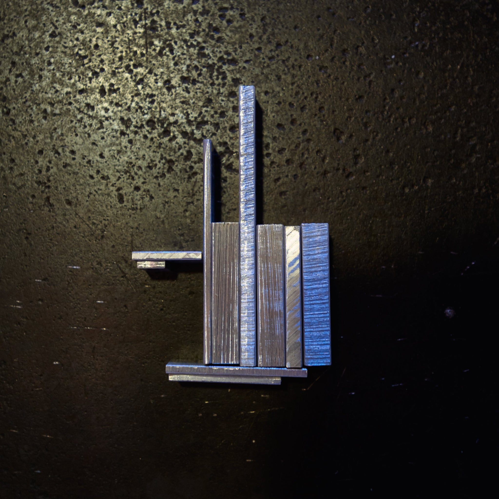 pieces of aluminium flat bar laid out on a steel bench with dramatic lighting on a steel bench