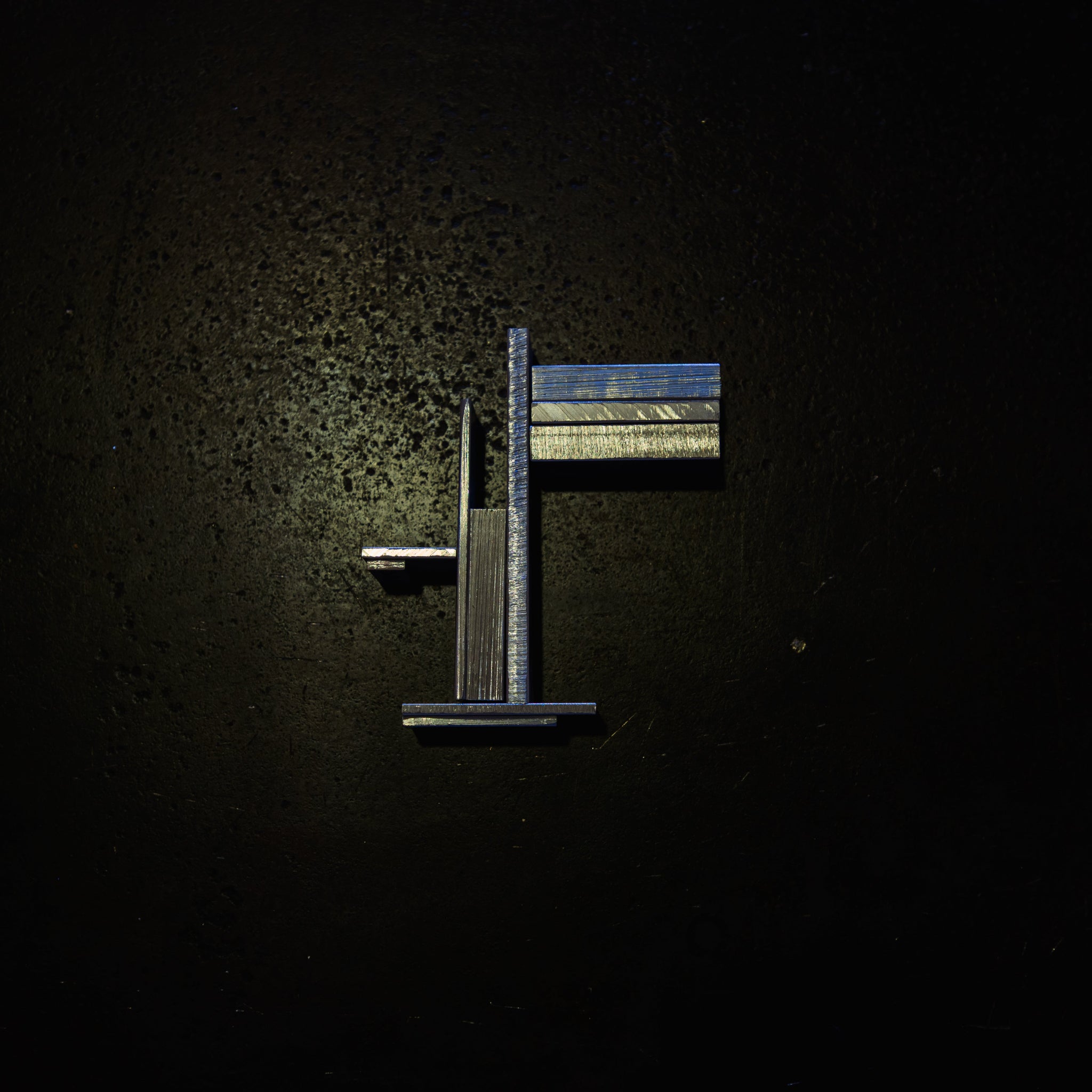 strategically laid out aluminium flat bar pieces on a steel bench with dramatic lighting