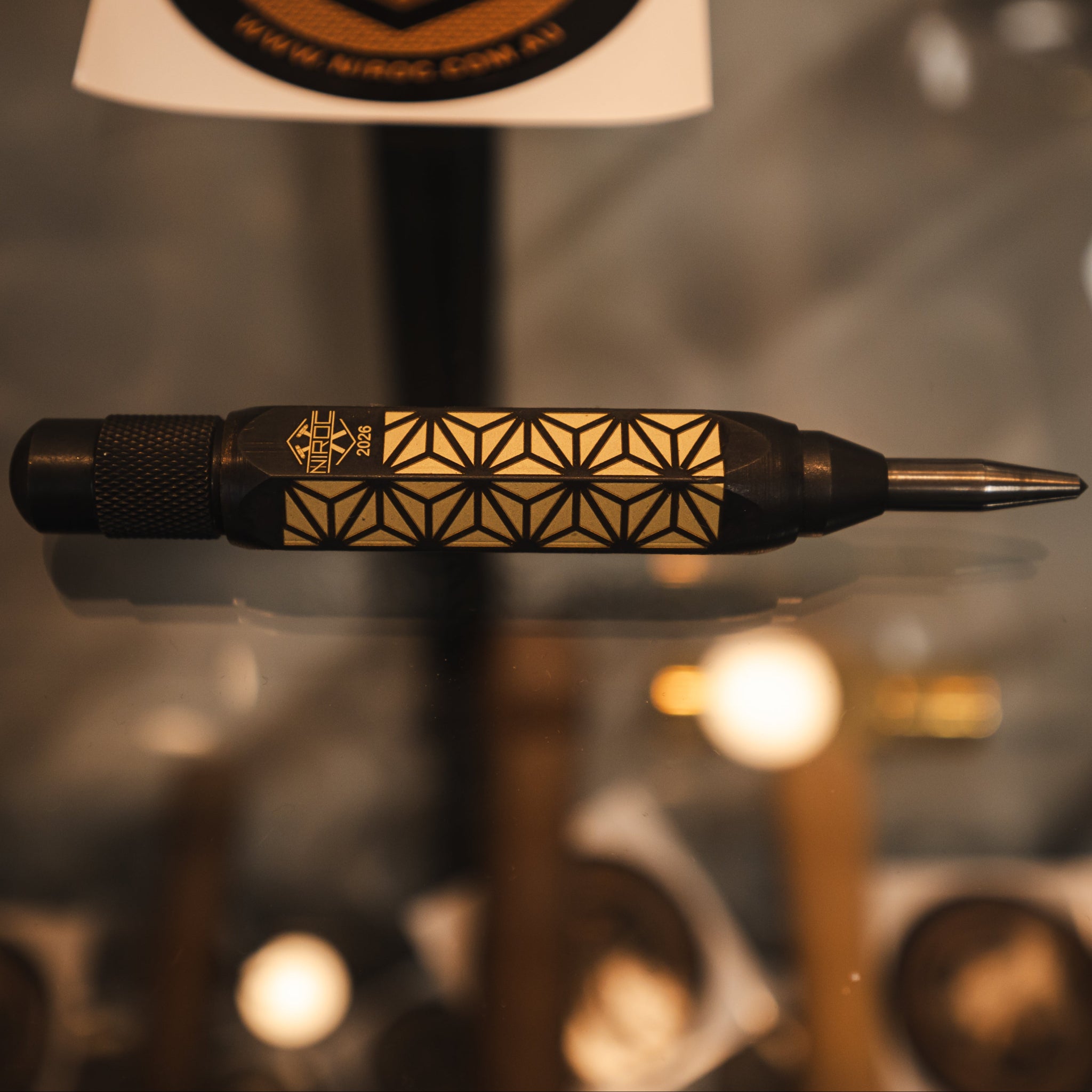 Niroc blackened brass with Kumiko laser engraved pattern on blurry glass background  
