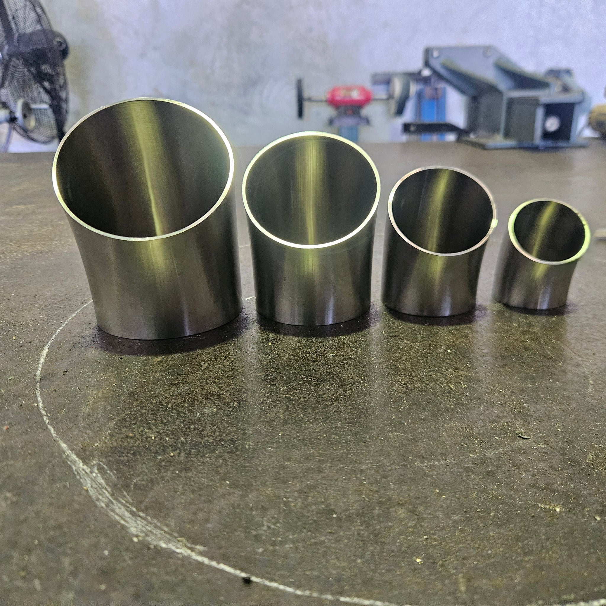 a group of 45 degree bends standing on a steel bench with workshop tooling in the background 