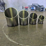 a group of 45 degree bends standing on a steel bench with workshop tooling in the background 