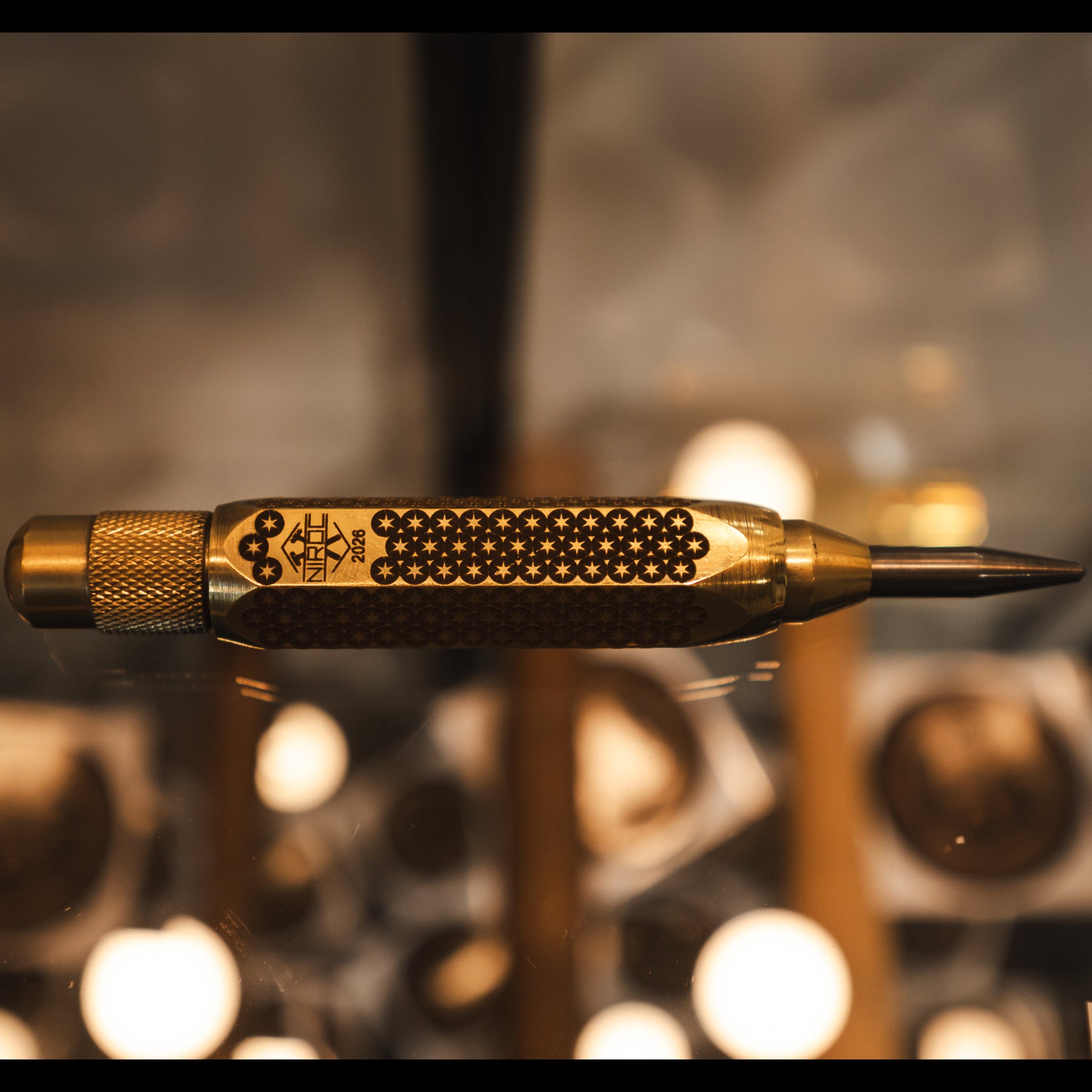 polished brass auto punch with carbide tip and a star pattern engraved into the body