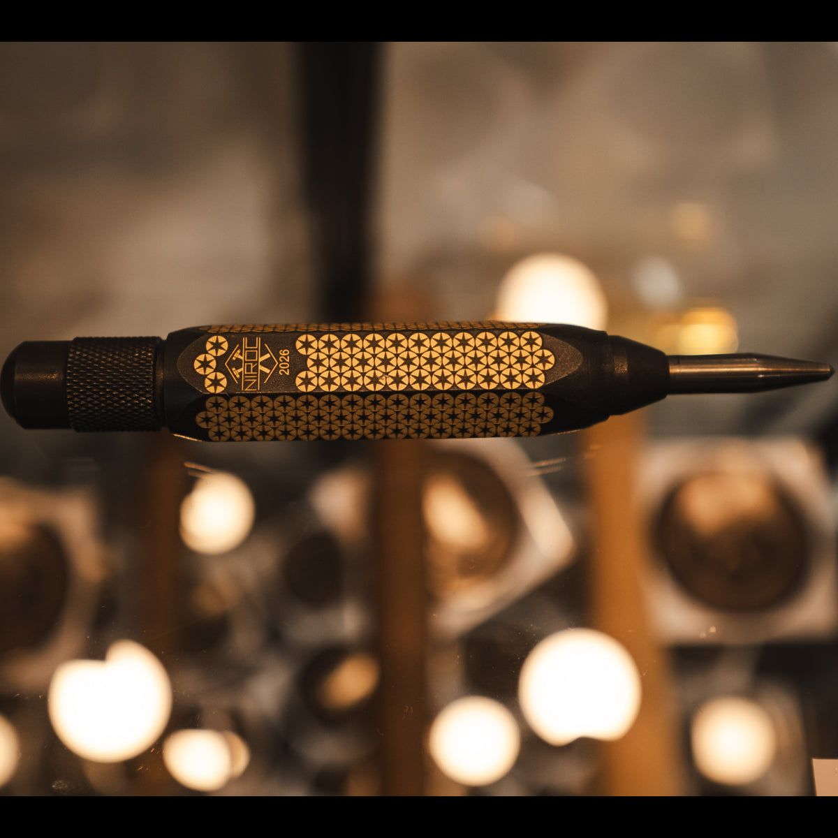 blackened brass auto punch with a star pattern engraved to the body