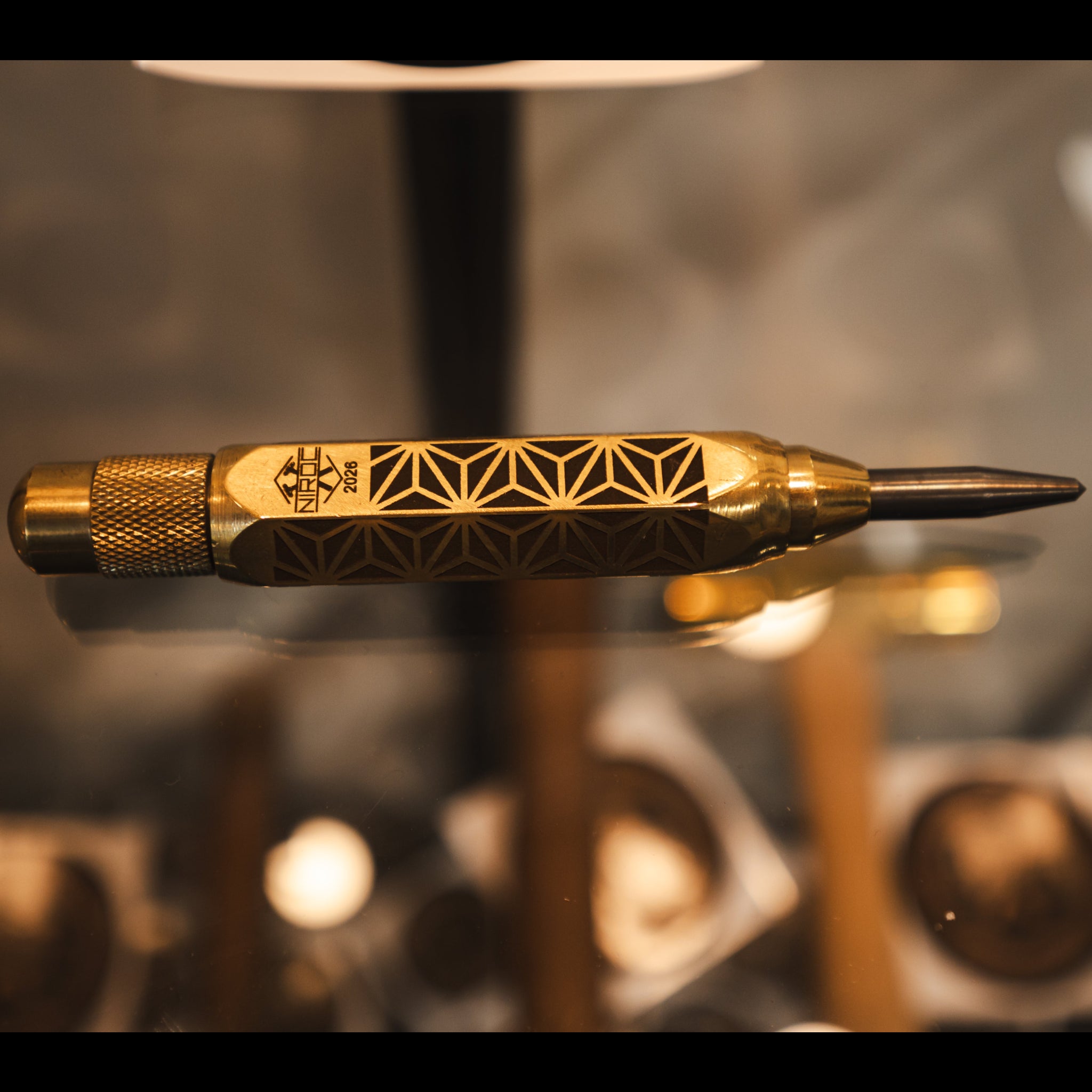 polished brass with kumiko pattern engraved into the body of this auto punch with a carbide tip